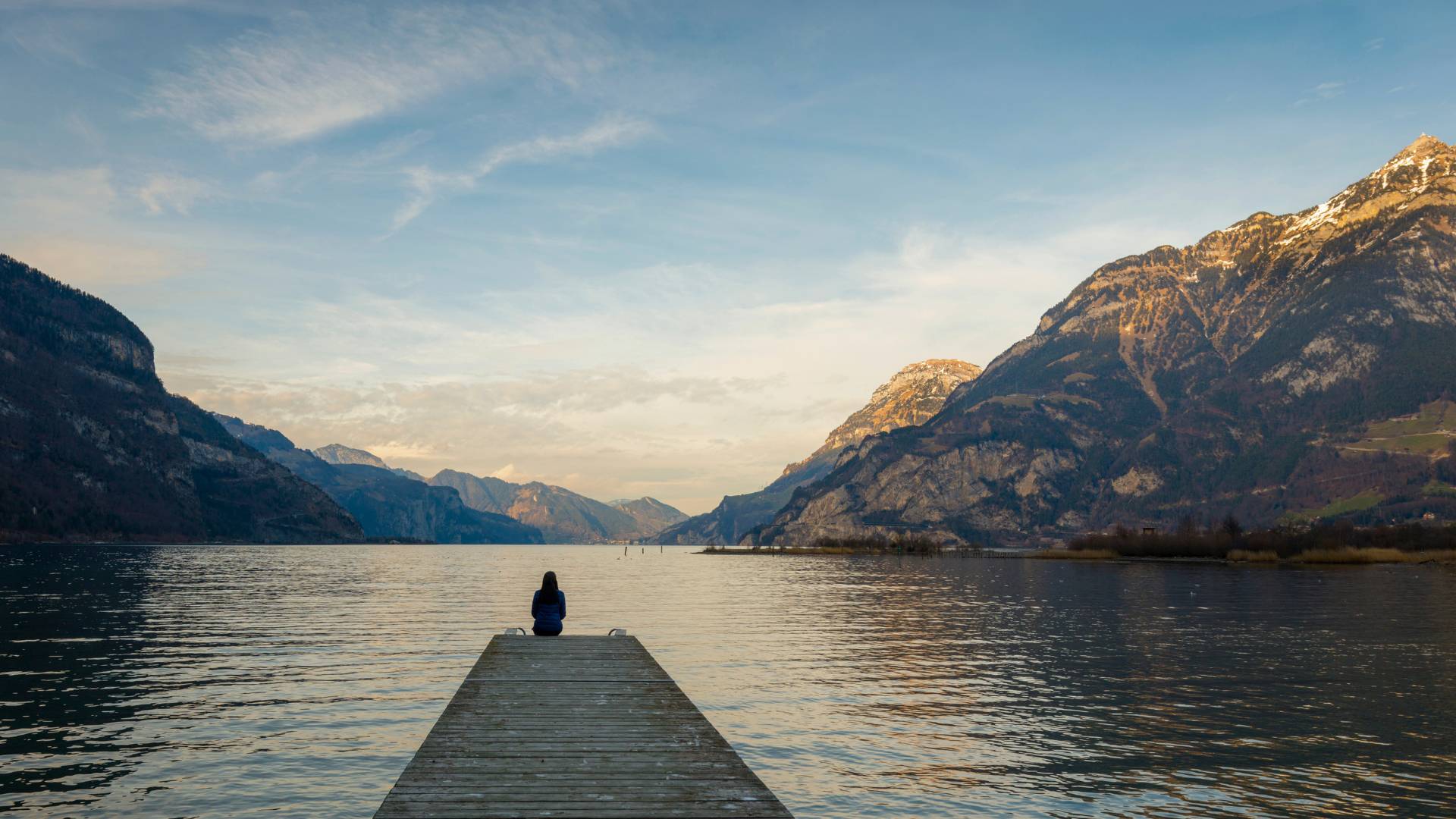 Woman sitting alone overlooking a beautiful lake in winter.